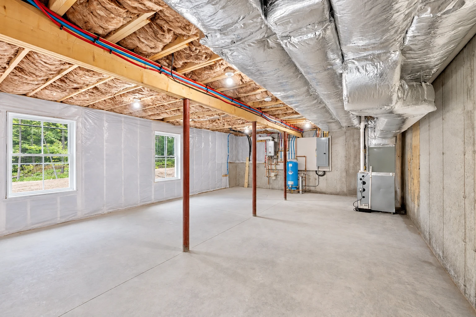 Basement with insulated ceiling joists, white-covered walls, exposed pipes, and silver HVAC ducts.